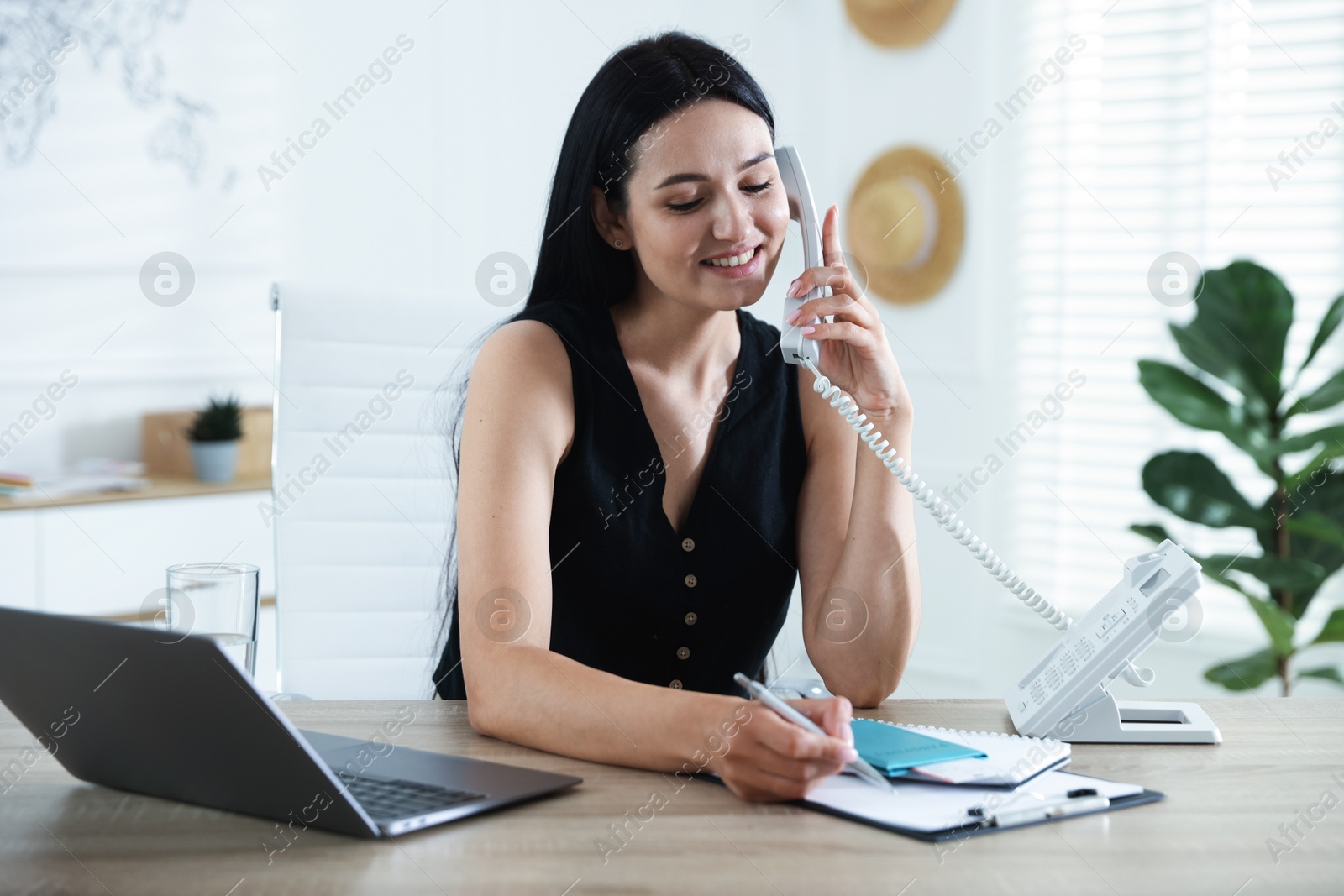 Travel agent working at wooden table in office Photo of Travel agent working at wooden table in office