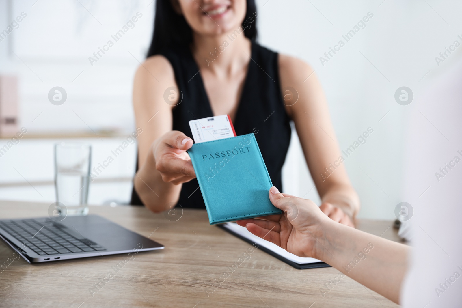 Travel agent giving passport with ticket to woman at wooden table in office, closeup Photo of Travel agent giving passport with ticket to woman at wooden table in office, closeup