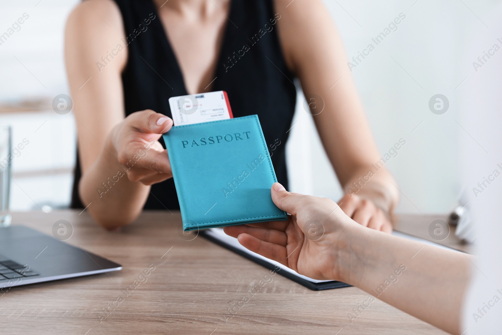Travel agent giving passport with ticket to woman at wooden table in office, closeup Photo of Travel agent giving passport with ticket to woman at wooden table in office, closeup