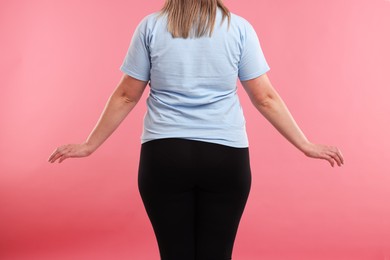 Photo of Weight loss. Plus size woman on pink background, closeup