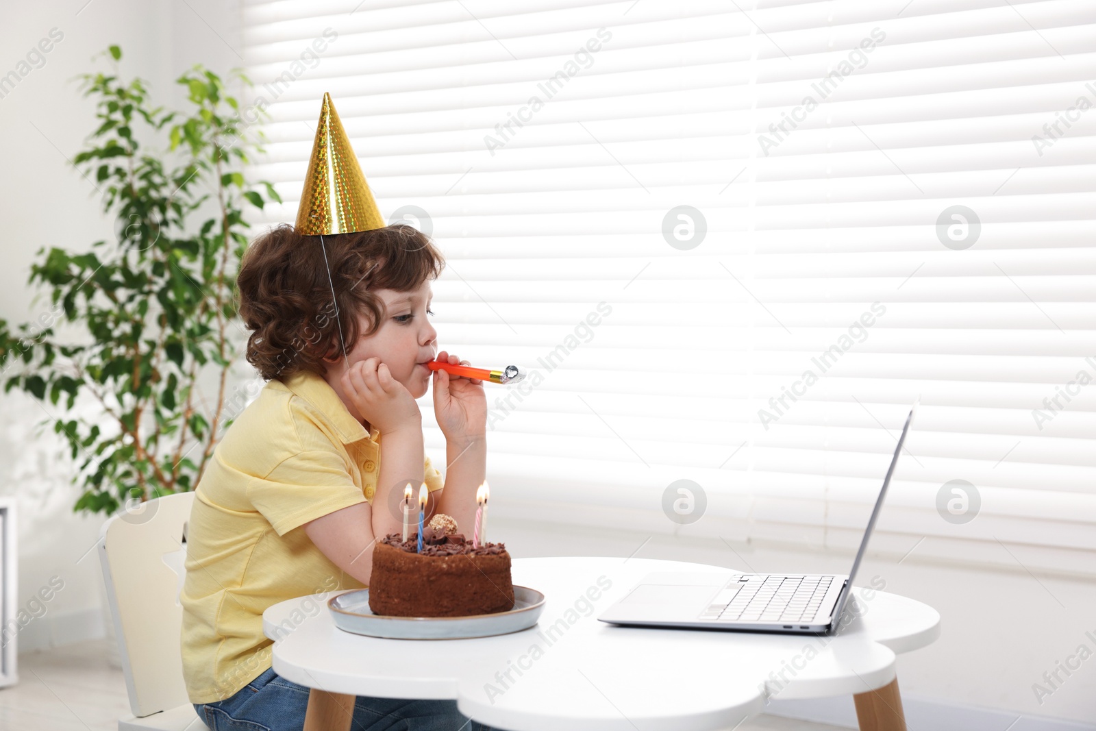 Little boy celebrating his birthday while having video call via laptop at table indoors. Space for text Photo of Little boy celebrating his birthday while having video call via laptop at table indoors. Space for text