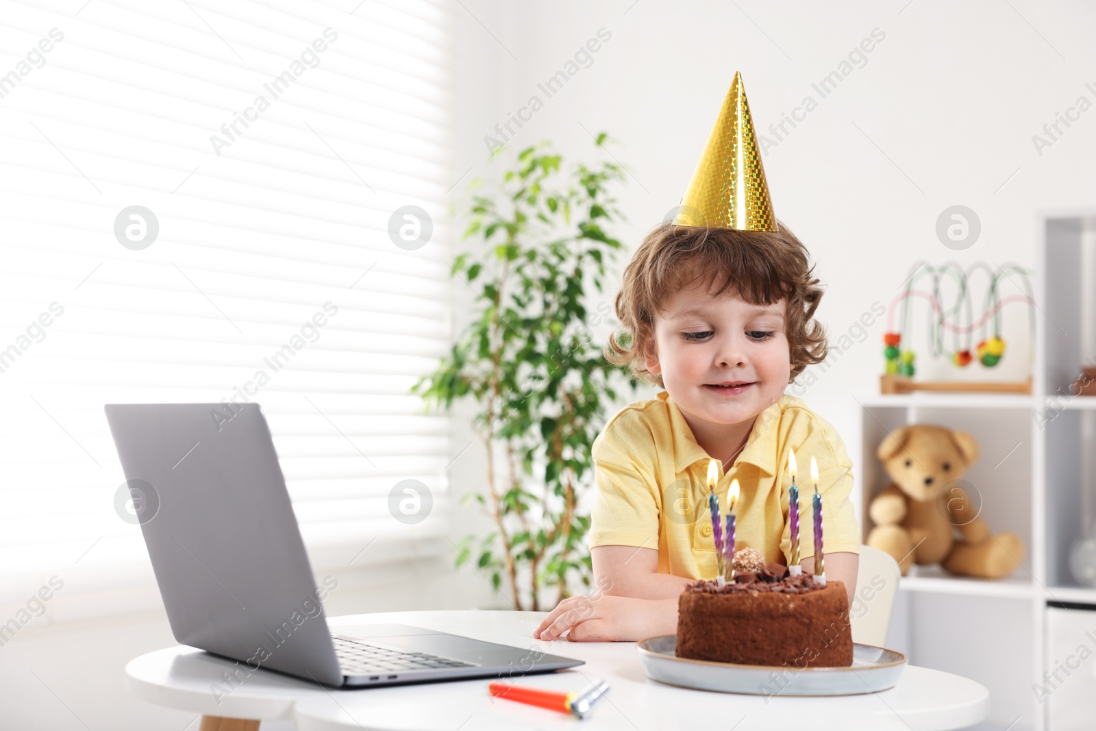 Birthday celebration. Little boy with cake having video call via laptop at table indoors. Space for text Photo of Birthday celebration. Little boy with cake having video call via laptop at table indoors. Space for text