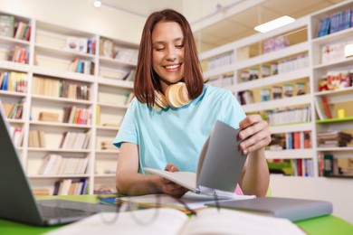 Photo of Student with laptop studying at table in library, low angle view