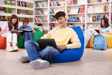 Photo of Student with laptop studying on bean bag in library