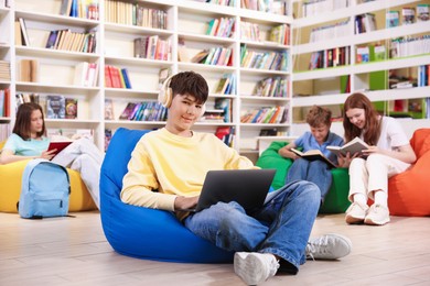 Photo of Student with laptop studying on bean bag in library