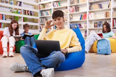 Photo of Student with laptop studying on bean bag in library