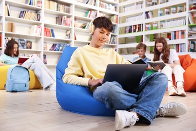 Photo of Student with laptop studying on bean bag in library