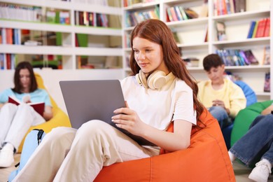 Photo of Student with laptop studying on bean bag in library
