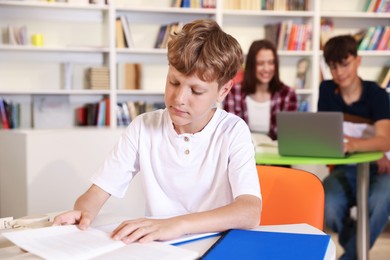 Photo of Student with books studying at table in library