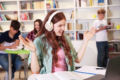 Photo of Student with laptop studying at table in library