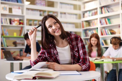 Photo of Student with books studying at table in library