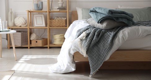 Photo of Cozy bed with soft linens and shelving unit with decor in stylish room. Home textile