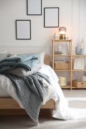 Photo of Cozy bed with soft linens and shelving unit with decor in stylish room. Home textile