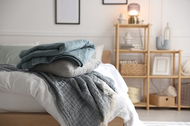 Photo of Cozy bed with soft linens and shelving unit with decor in stylish room. Home textile