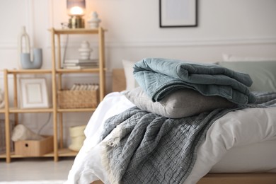 Photo of Cozy bed with soft linens and shelving unit with decor in stylish room. Home textile