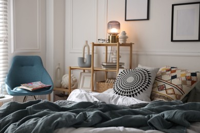 Photo of Cozy bed with soft linens, furniture and decor in stylish room. Home textile