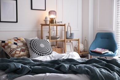 Photo of Cozy bed with soft linens, furniture and decor in stylish room. Home textile
