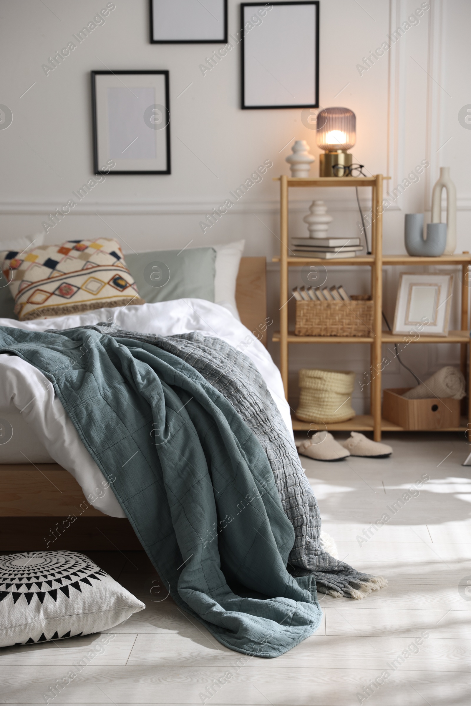 Cozy bed with soft linens and shelving unit with decor in stylish room. Home textile Photo of Cozy bed with soft linens and shelving unit with decor in stylish room. Home textile