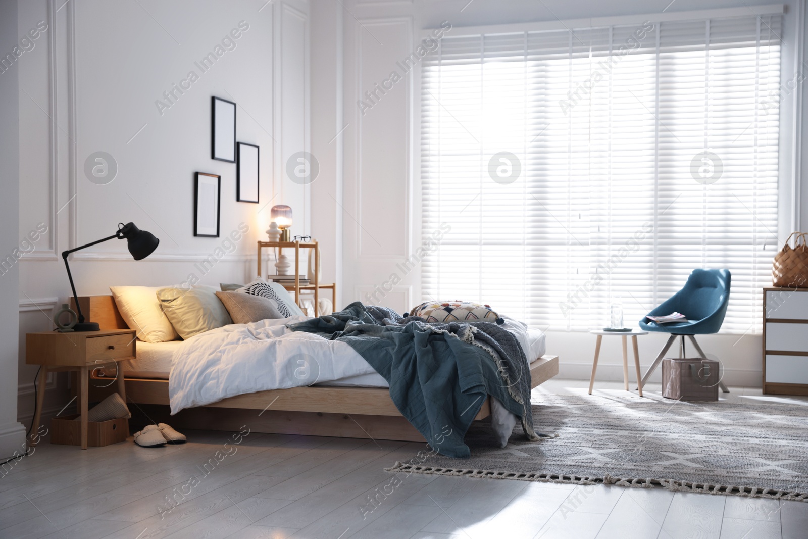 Cozy bed with soft linens, furniture and decor in stylish room. Home textile Photo of Cozy bed with soft linens, furniture and decor in stylish room. Home textile