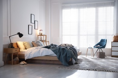 Photo of Cozy bed with soft linens, furniture and decor in stylish room. Home textile