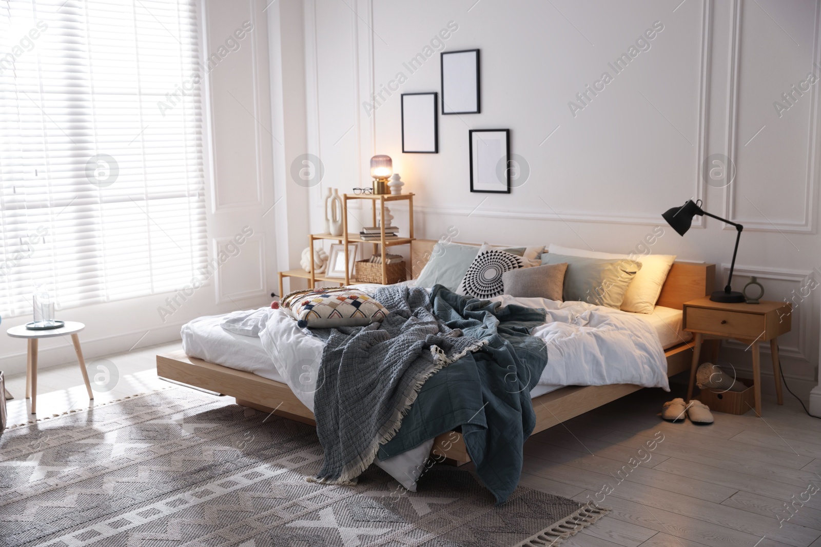 Cozy bed with soft linens, furniture and decor in stylish room. Home textile Photo of Cozy bed with soft linens, furniture and decor in stylish room. Home textile
