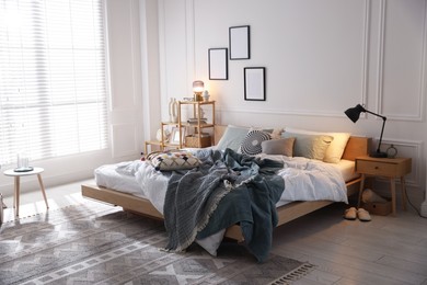 Photo of Cozy bed with soft linens, furniture and decor in stylish room. Home textile