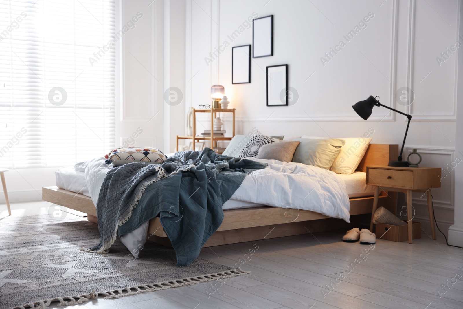 Cozy bed with soft linens, nightstand and lamp in stylish room. Home textile Photo of Cozy bed with soft linens, nightstand and lamp in stylish room. Home textile