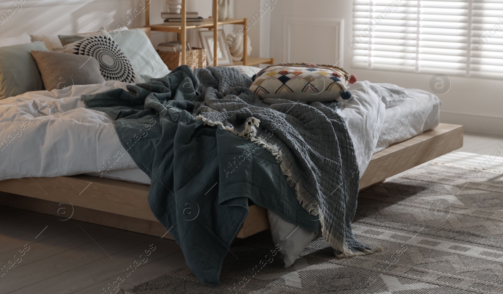 Large bed with soft linens in stylish room. Home textile Photo of Large bed with soft linens in stylish room. Home textile