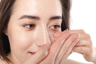 Photo of Woman putting in contact lens on white background, closeup
