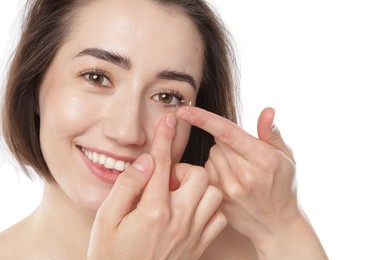 Photo of Woman putting in contact lens on white background, closeup