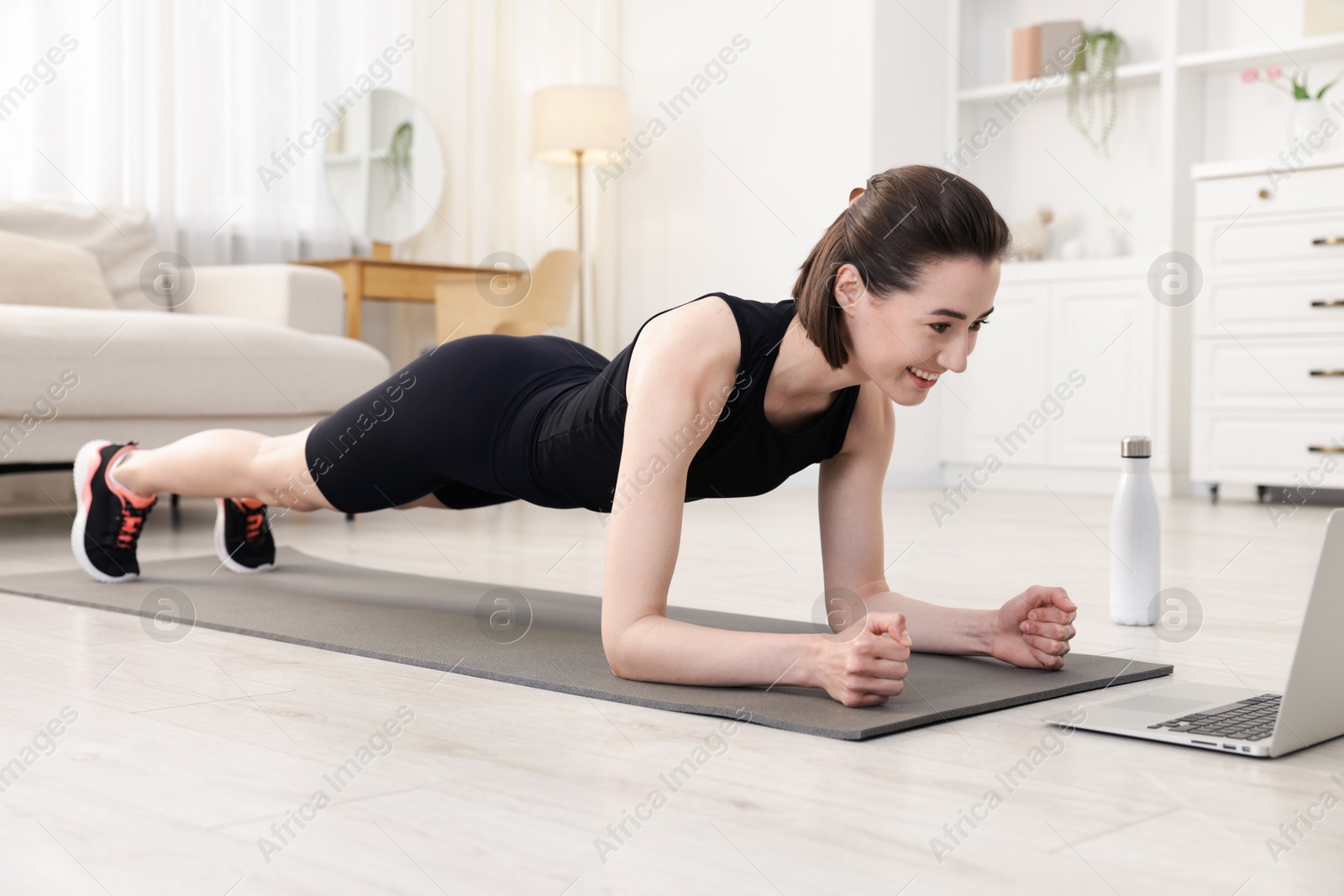 Woman doing plank exercise during online class with coach at home. Sport and healthy lifestyle Photo of Woman doing plank exercise during online class with coach at home. Sport and healthy lifestyle
