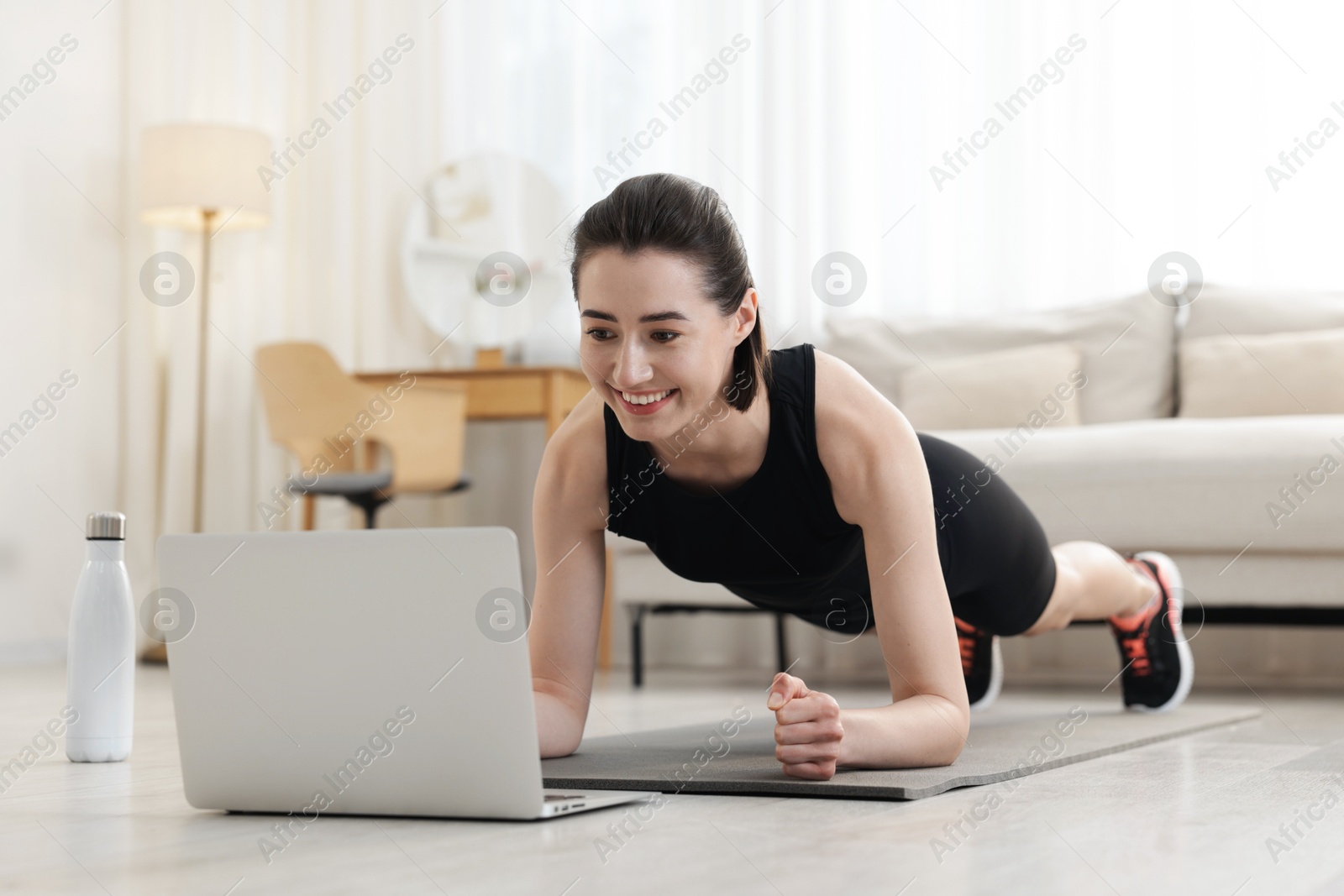 Woman doing plank exercise during online class with coach at home. Sport and healthy lifestyle Photo of Woman doing plank exercise during online class with coach at home. Sport and healthy lifestyle