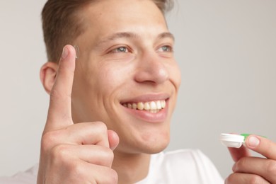 Photo of Man with contact lens and case on light background, closeup