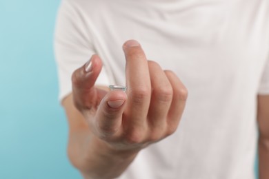 Photo of Man with contact lens on light blue background, closeup