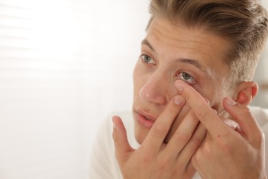 Photo of Man putting in contact lens at home, closeup. Space for text