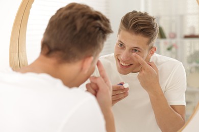 Photo of Man putting in contact lens near mirror at home