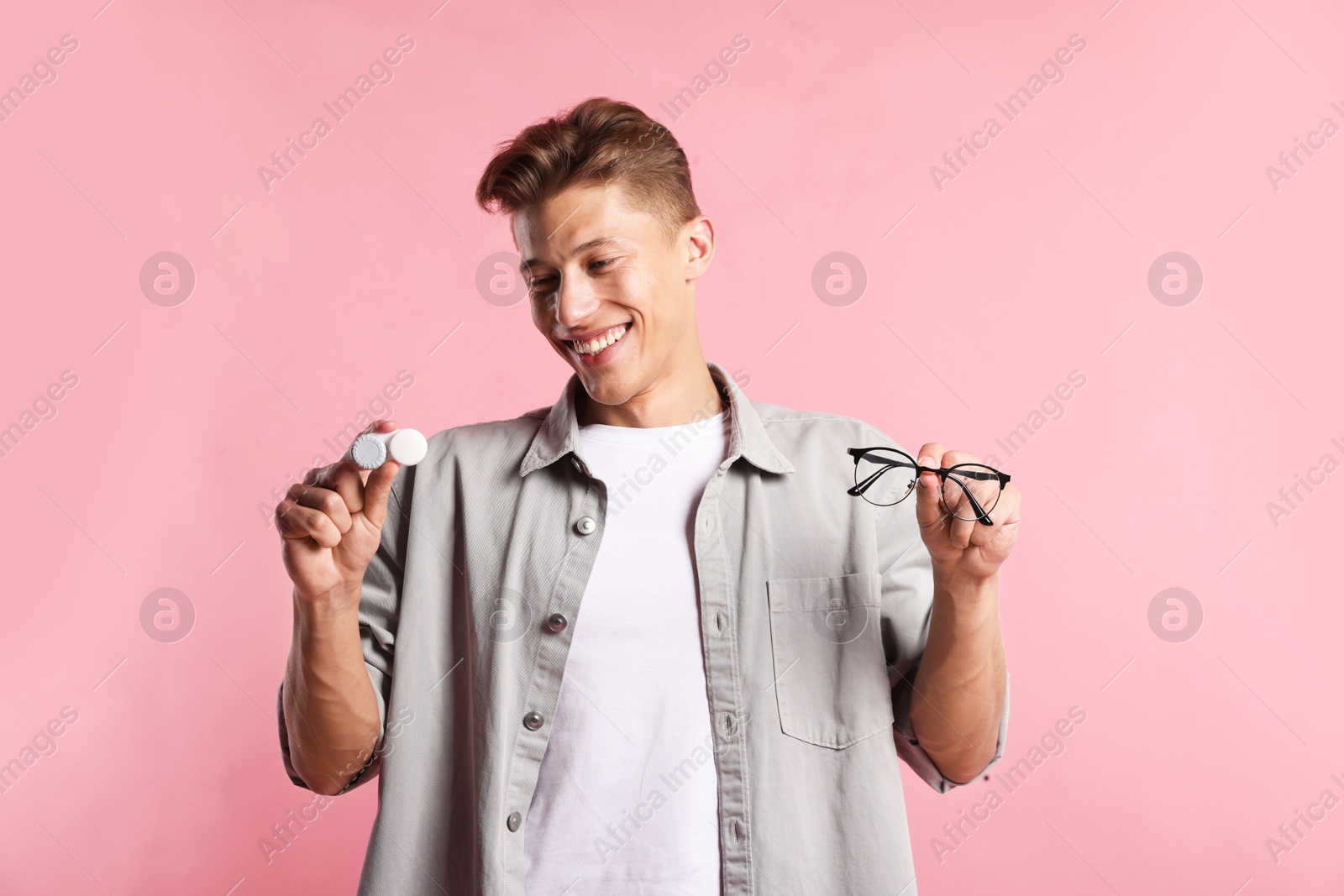 Man choosing between glasses and contact lenses on pink background Photo of Man choosing between glasses and contact lenses on pink background
