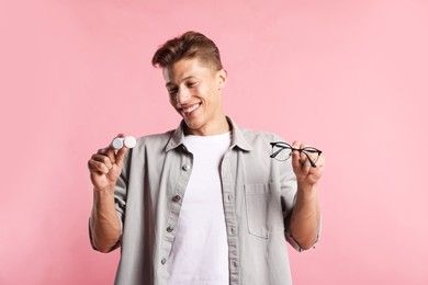 Photo of Man choosing between glasses and contact lenses on pink background