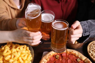 Photo of Friends with beer and snacks at wooden table, closeup