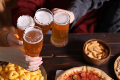 Photo of Friends with beer and snacks at wooden table, closeup