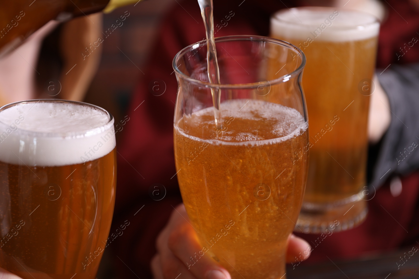 Pouring beer into woman's glass indoors, closeup Photo of Pouring beer into woman's glass indoors, closeup