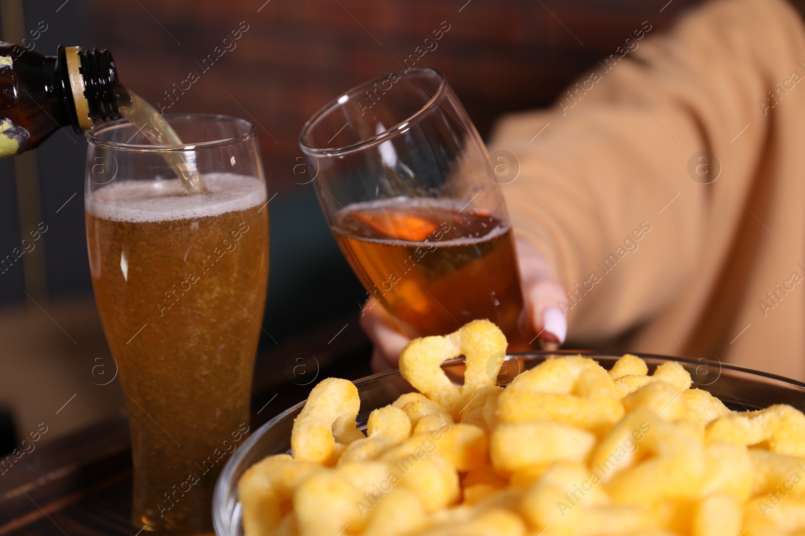 Pouring beer into woman's glass at wooden table, closeup Photo of Pouring beer into woman's glass at wooden table, closeup
