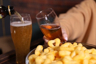 Photo of Pouring beer into woman's glass at wooden table, closeup