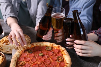 Photo of Friends with beer and snacks at grey table, closeup