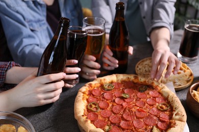 Photo of Friends with beer and snacks at grey table, closeup