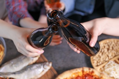 Photo of Friends with beer and snacks at grey table, closeup