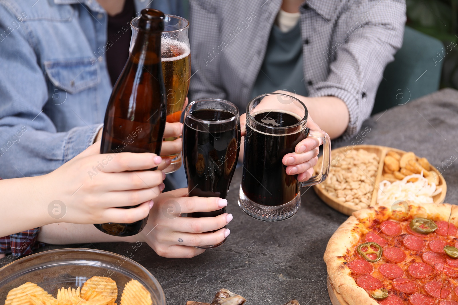 Friends with beer and snacks at grey table, closeup Photo of Friends with beer and snacks at grey table, closeup