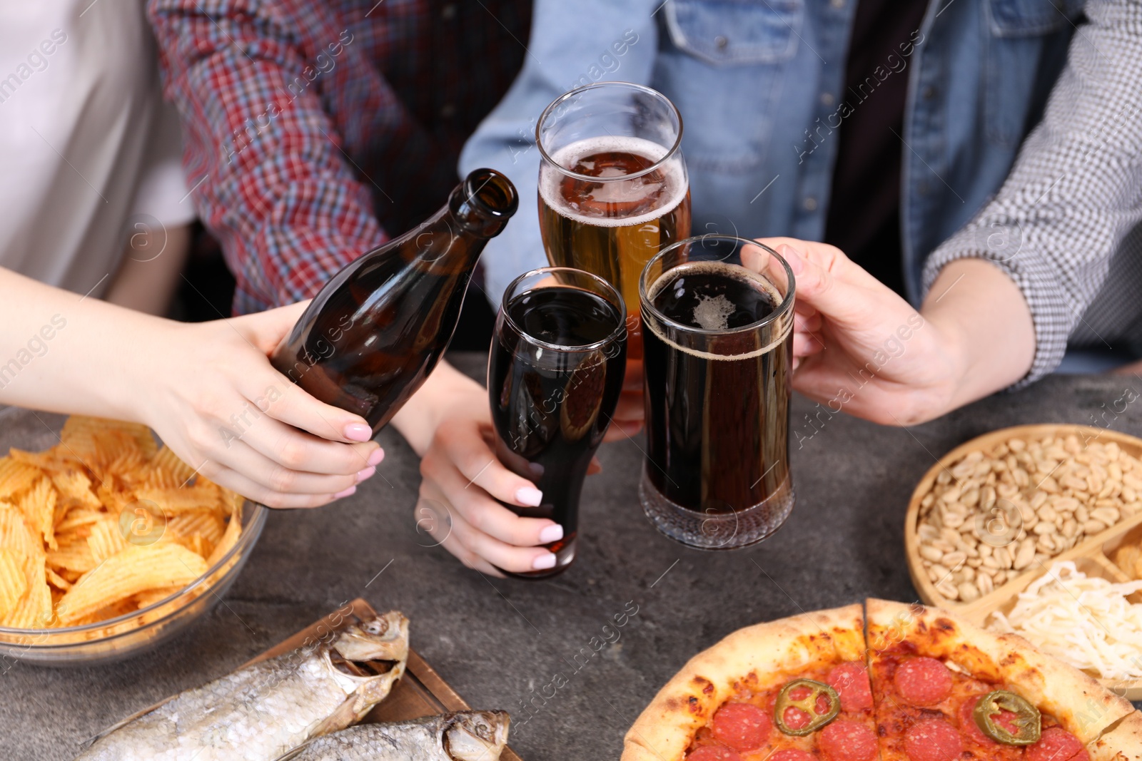 Friends with beer and snacks at grey table, closeup Photo of Friends with beer and snacks at grey table, closeup