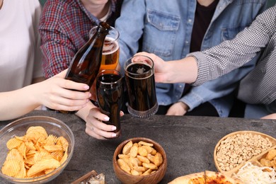Photo of Friends with beer and snacks at grey table, closeup