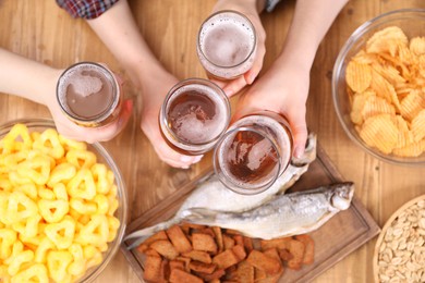 Photo of Friends with beer and snacks at wooden table, top view